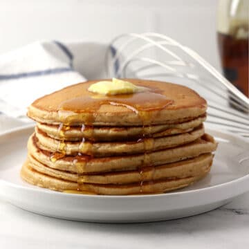 A stack of pancakes with butter and syrup.