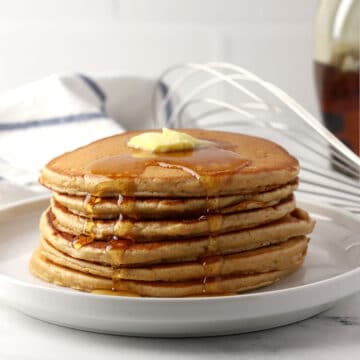 A stack of pancakes with butter and syrup.