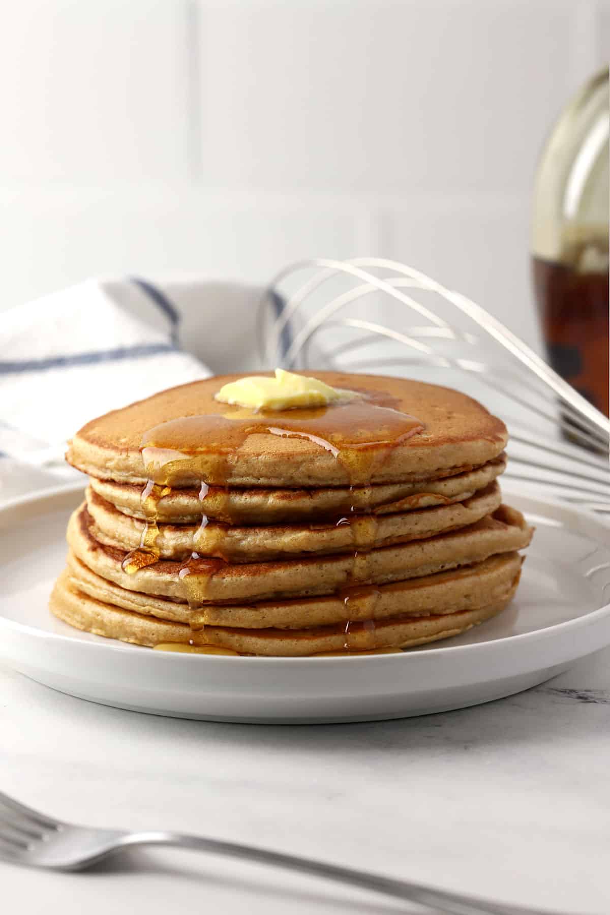 A stack of pancakes with butter and syrup.