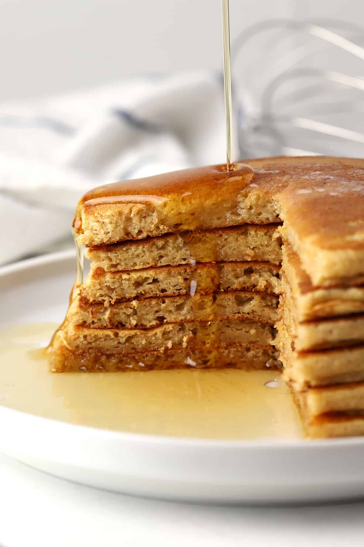 A sliced stack of pancakes with butter and syrup.