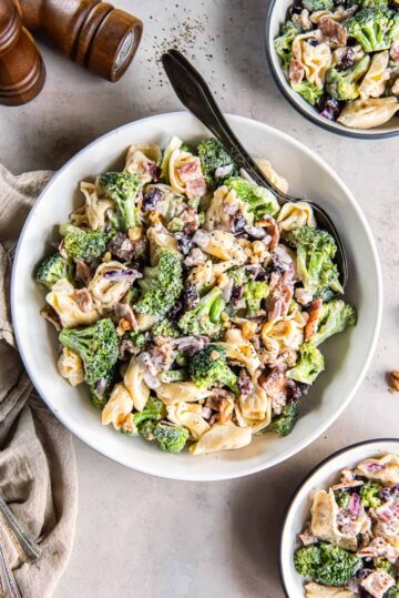 A bowl of broccoli and tortellini in a creamy dressing.