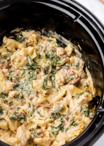 A crockpot filled with creamy tortellini.