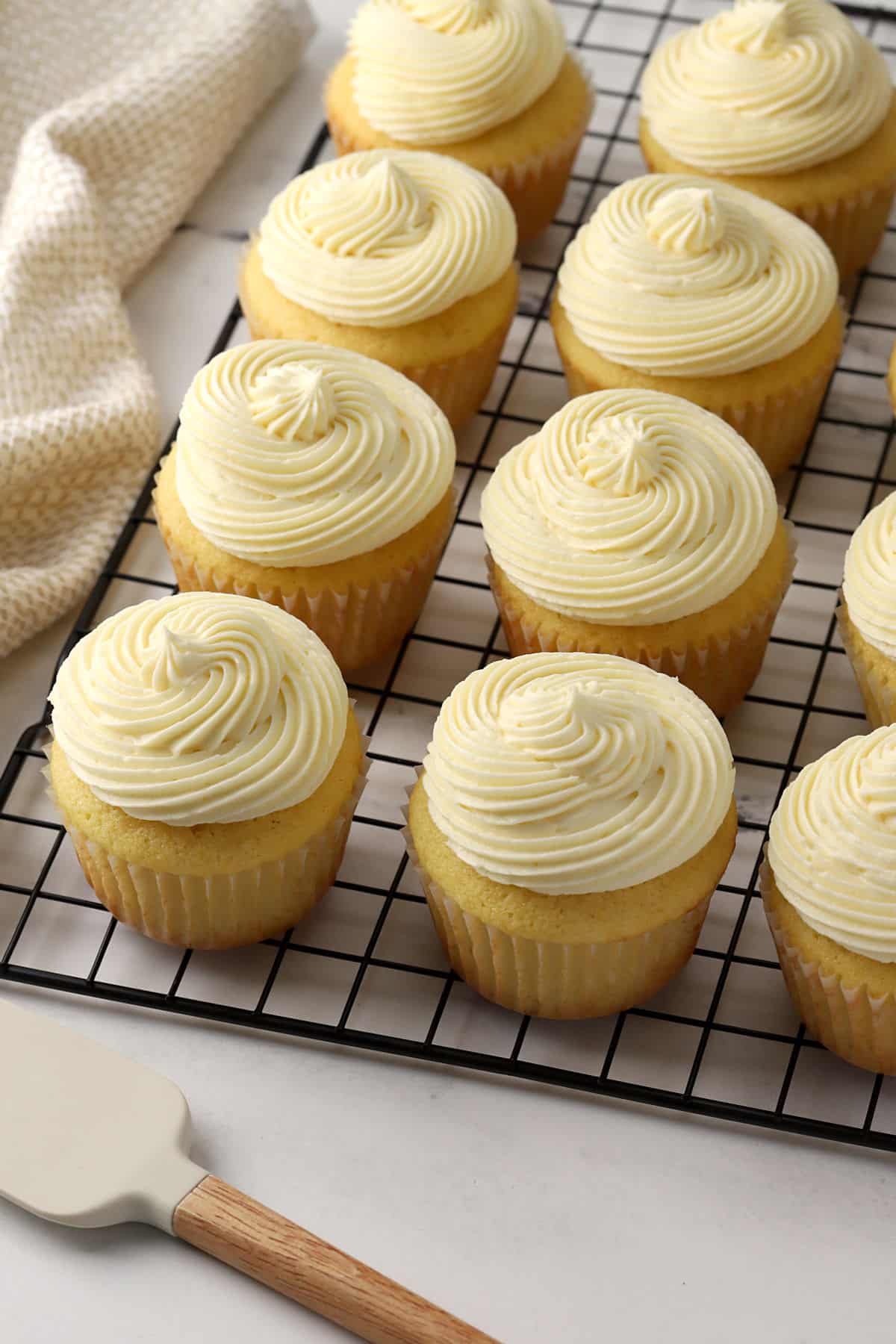 Frosted buttermilk cupcakes on a cooling rack.