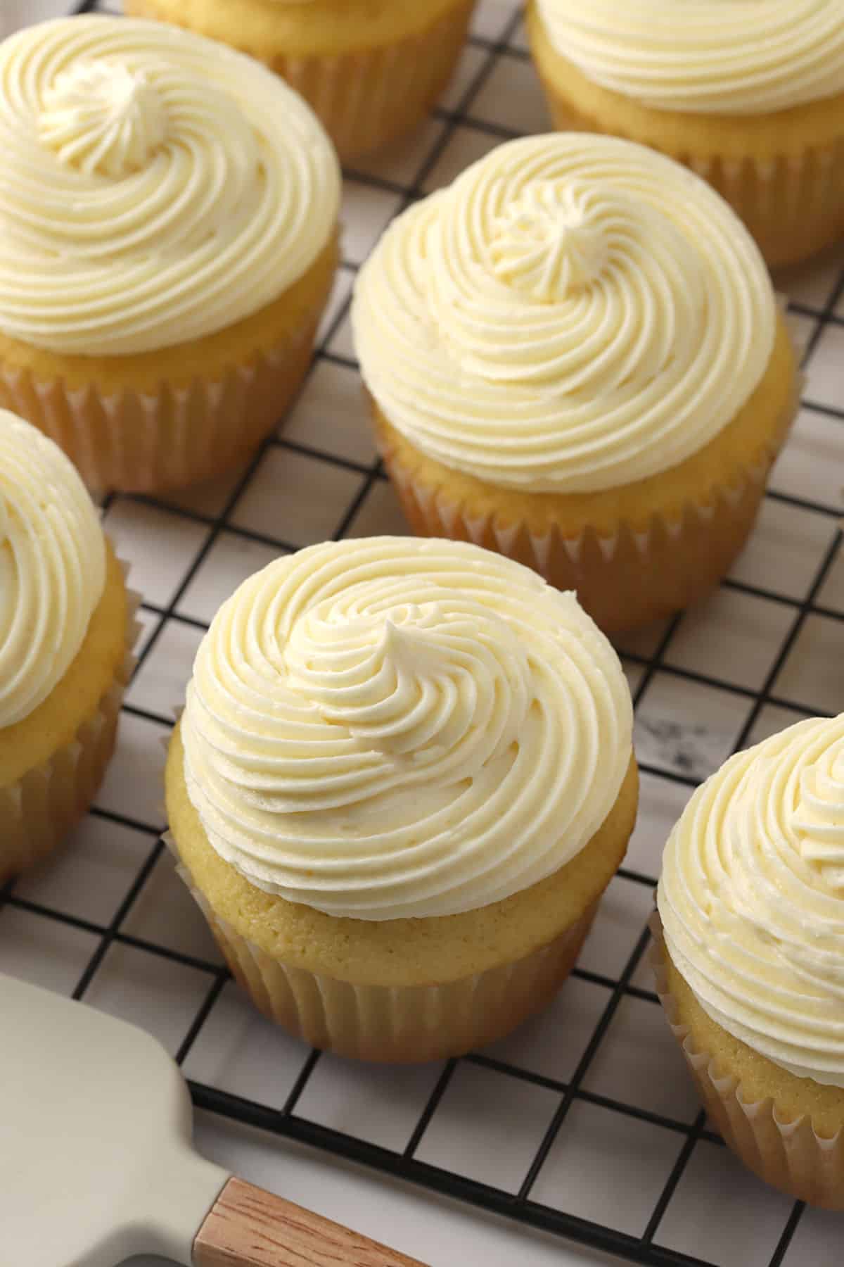 Frosted cupcakes on a cooling rack.