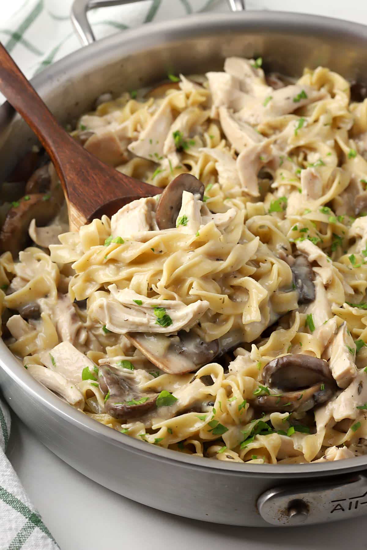 Close up of chicken and noodles in a saute pan.