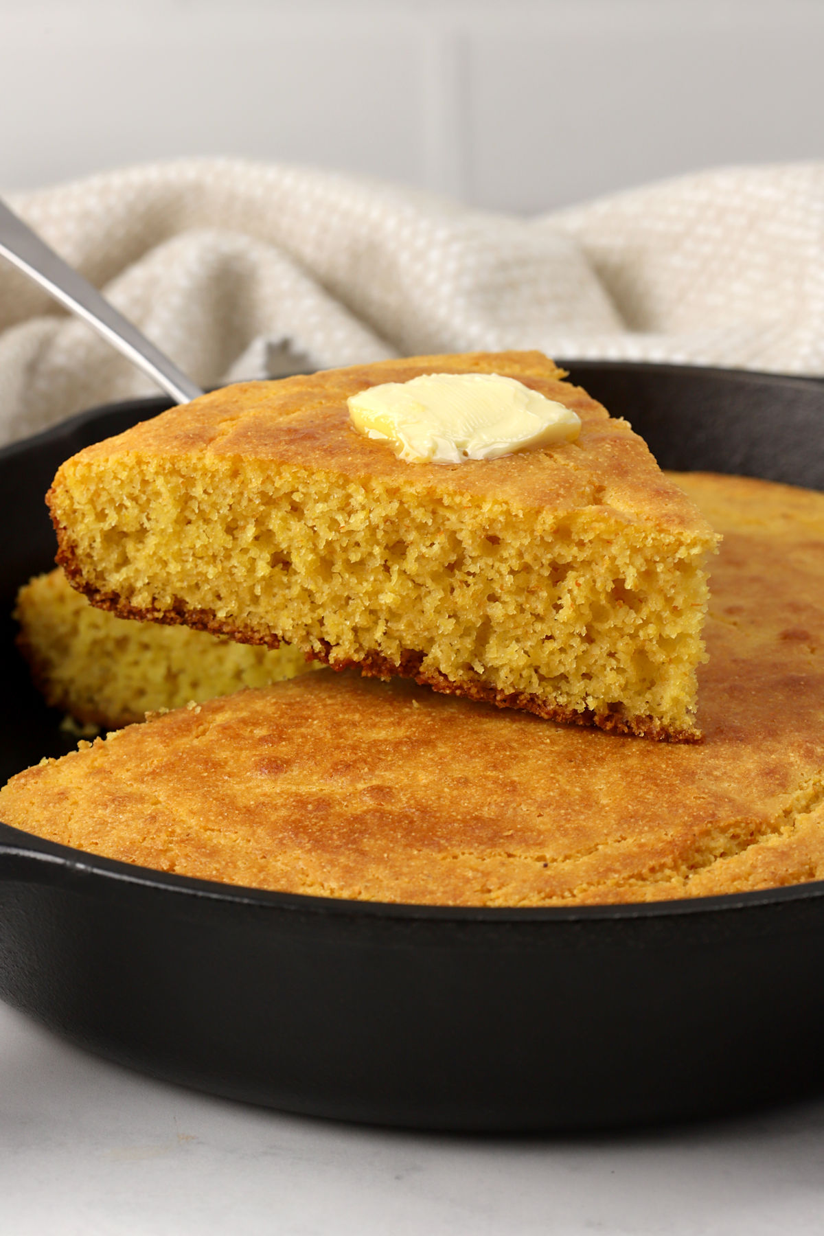 Slice of cornbread with butter on top.