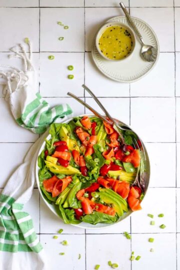 A bowl of salad with avocados and smoked salmon.