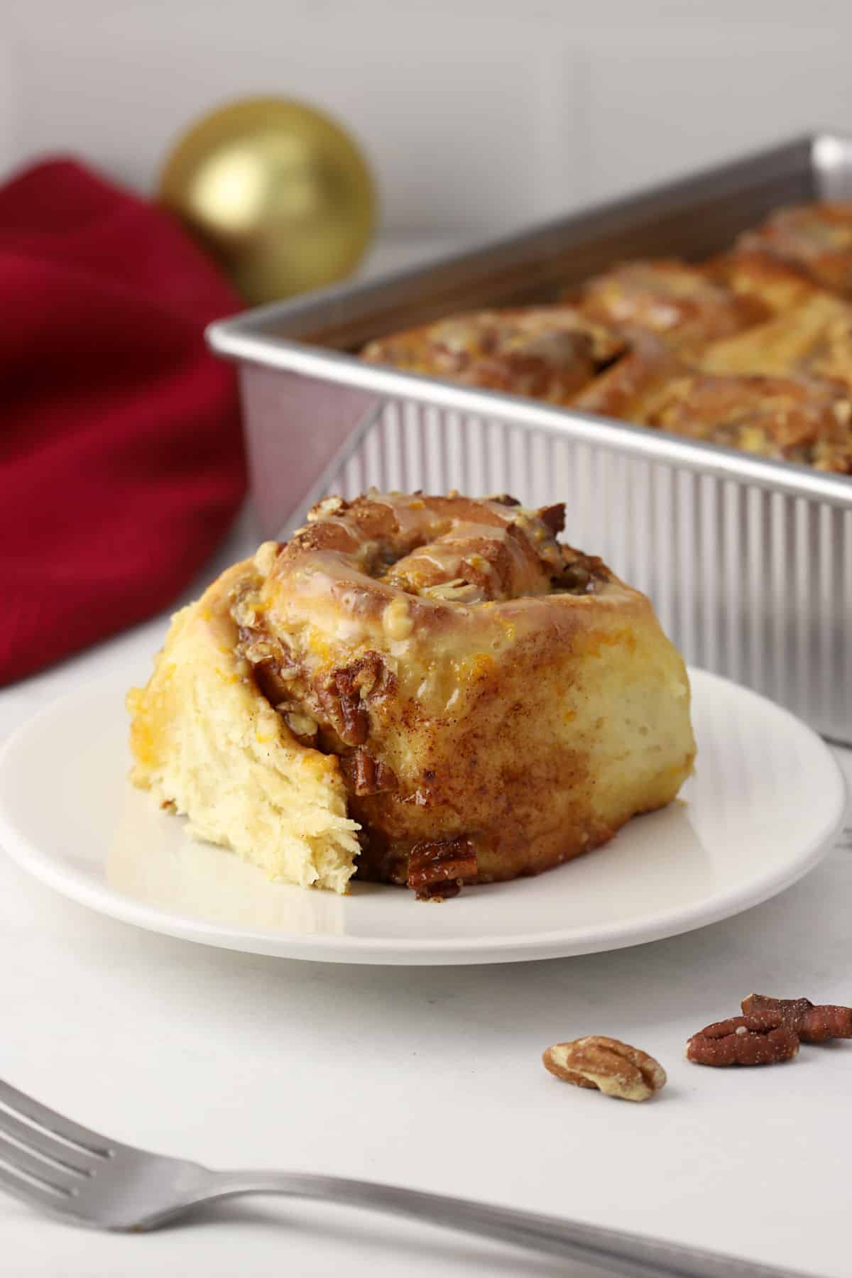A cinnamon roll on a plate with a pan in the background.