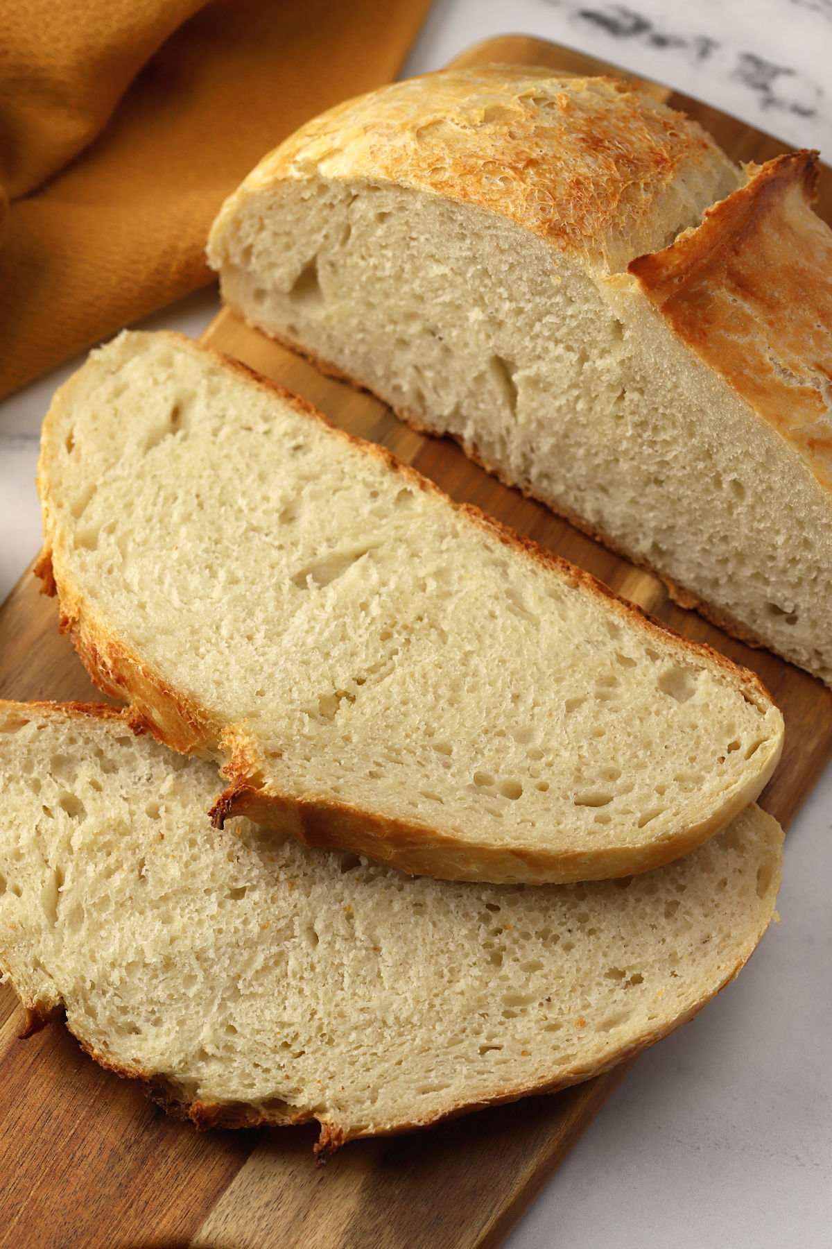 No knead bread sliced on a wooden cutting board.
