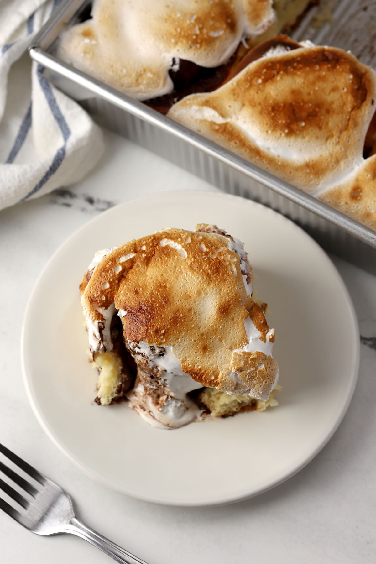 S'mores cinnamon roll next to a pan of more cinnamon rolls.